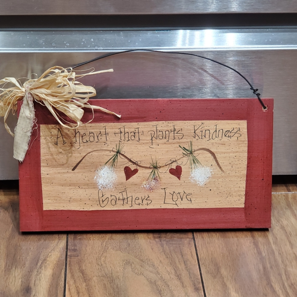 Hanging Wood Sign Reads, A Heart That Plants Kindness Gathers Love